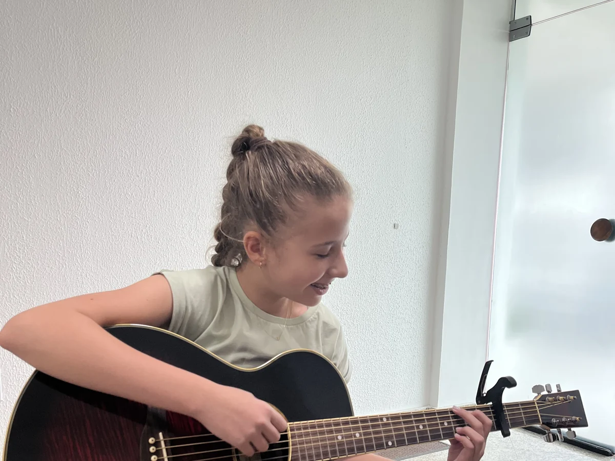 Aluna tocando violão em aula na Tocante Centro Musical