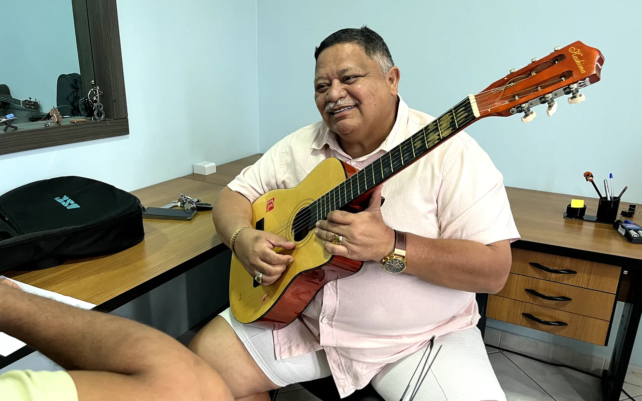 Aluno adulto tocando violão em aula na Tocante Centro Musical